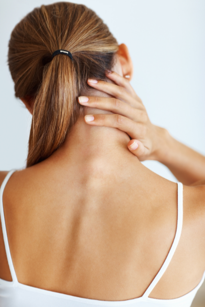 Woman with a ponytail touching her neck against a white background